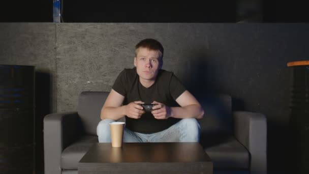 Расстроенный человек после проигрыша в онлайн-играх сидит на диване — стоковое видео