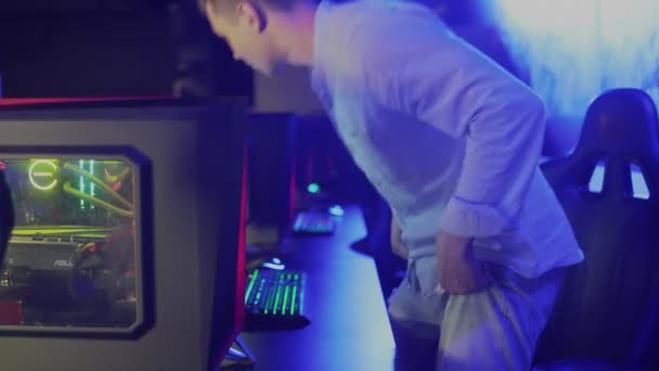 Joven jugador Pro Sentado en su ordenador y encendiendo el monitor — Vídeo de stock