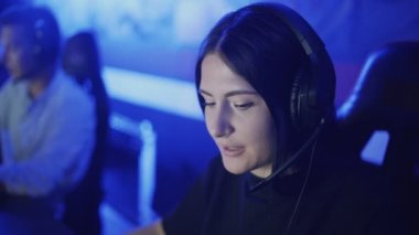 Modern bir bilgisayar kulübünde kulaklık takan mutlu bir kadın online oyun oynuyor..