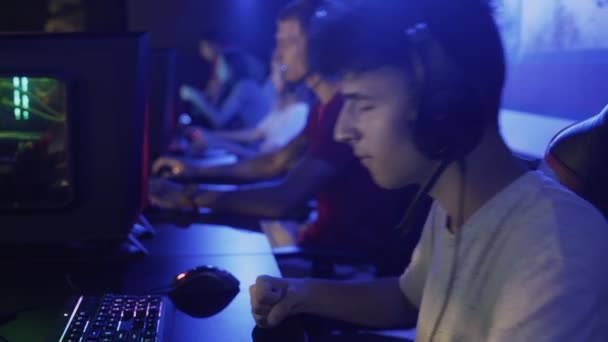 Концентрированный молодой человек сидит перед монитором и теряет жесткий уровень в видеоигре в компьютерном клубе — стоковое видео