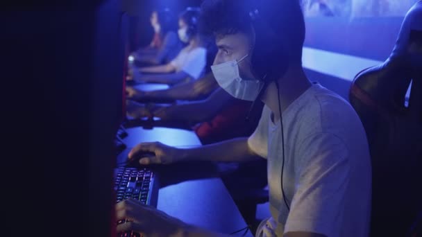 Fechar-se de Jovem Gamer na máscara facial perde em jogo de vídeo on-line no clube de computador moderno . — Vídeo de Stock