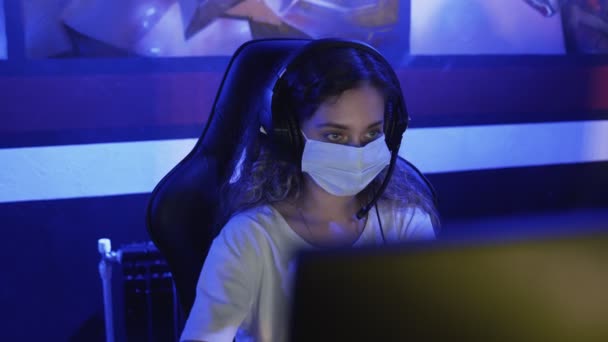 Primer plano de la joven jugadora en máscaras faciales juega en los videojuegos en el club de computadoras moderno. — Vídeo de stock
