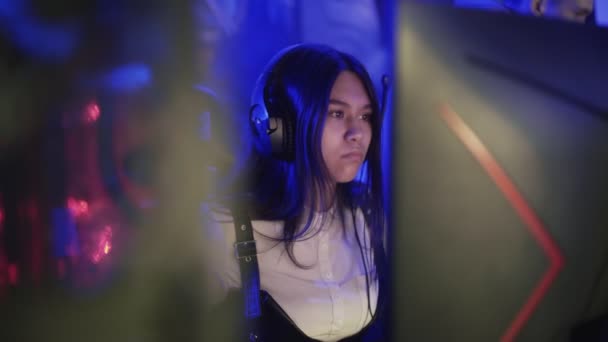 Konzentrierte junge Frau sitzt vor Monitor und spielt Videospiel im Computerclub — Stockvideo