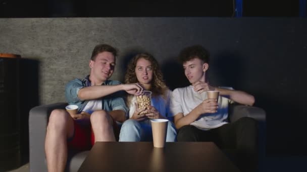 Na sala de estar três melhores amigos assistindo TV, e comeu pipocas — Vídeo de Stock