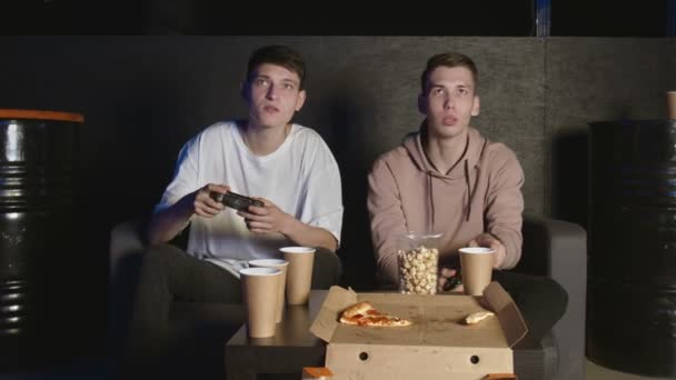 Deux amis masculins perdant dans le jeu vidéo, assis sur le canapé, amitié adolescente — Video