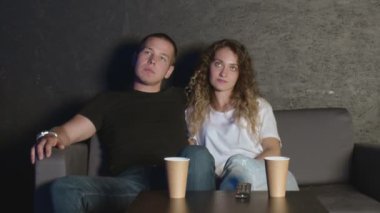 Kocasıyla kanepede oturup film tartışan mutlu, genç bir kadın..