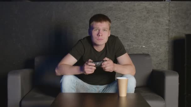 Jeune homme jouant jeu de console devant la caméra, battant son adversaire en ligne. Homme blanc sur canapé. — Video