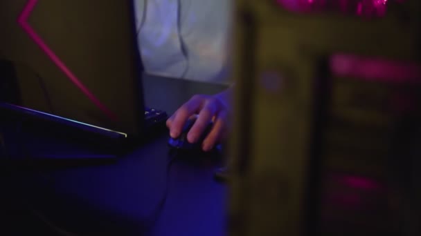 Joven concentrado se sienta frente al monitor y juega duro nivel en el videojuego en el club de computadoras — Vídeo de stock