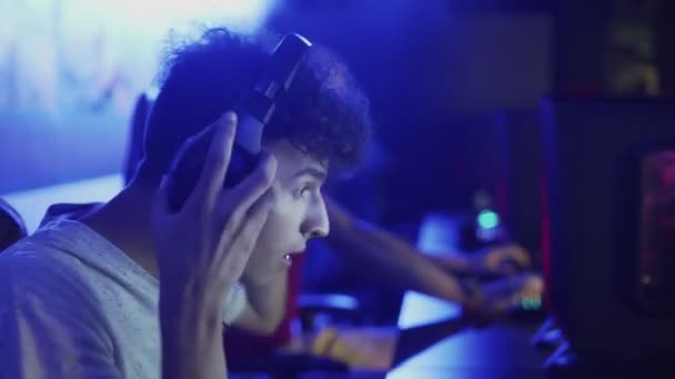 Jovem usa fones de ouvido e se prepara para jogar em um jogo de vídeo — Vídeo de Stock