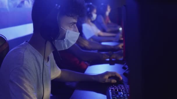 Primer plano de Young Gamer en la máscara de la cara pierde en el videojuego en línea en el club de ordenador moderno. — Vídeo de stock