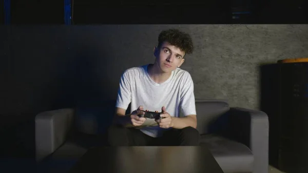 Portrait of young concentrated man playing video games sitting on couch indoors — Stock Photo, Image