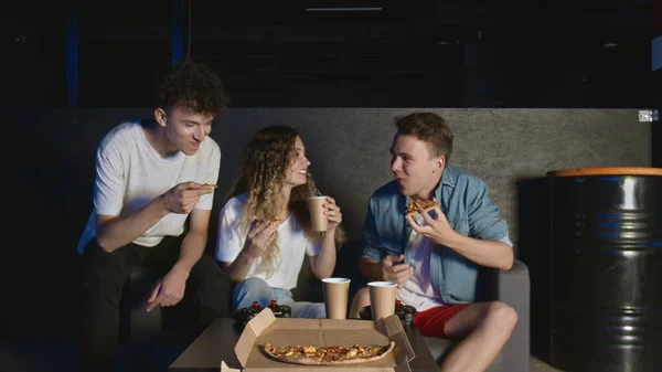 Jonge vrienden eten pizza en praten in de donkere kamer — Stockfoto