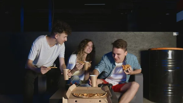 Jonge vrienden eten pizza en praten in de donkere kamer — Stockfoto