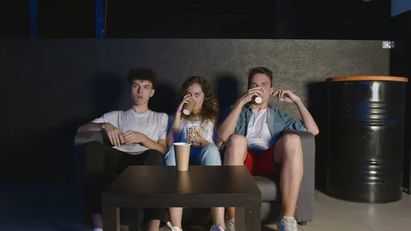 Im Wohnzimmer sitzen drei beste Freunde vor dem Fernseher und essen Popcorn — Stockfoto