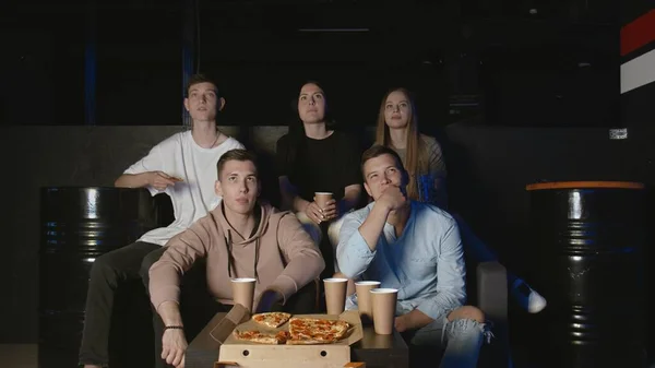 Les jeunes amis mangent des pizzas et regardent une émission de télévision amusante — Photo