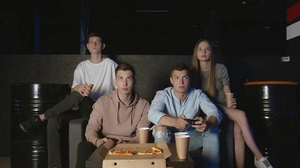 Hem fest vänner har roligt tillsammans äta pizza och spela på en spelkonsol — Stockfoto