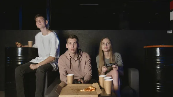 Glada sällskap spelar i konsolspelet, flicka mot pojke. Äter pizza — Stockfoto