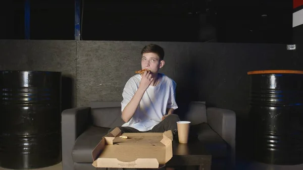 Jeune homme mangeant de la pizza et regardant la télévision à la maison se détendre sur le canapé — Photo