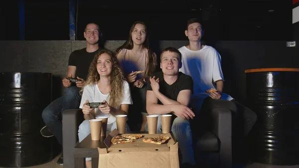 Mejores amigos relajándose en el sofá de la sala de estar, jugando videojuegos y comiendo pizza — Foto de Stock