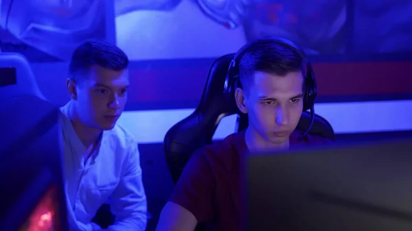 Genç adam, modern siber spor kulübünde video oyunu oynarken arkadaşına tavsiye veriyor. — Stok fotoğraf
