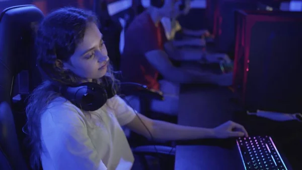 Vista lateral de la mujer molesta se sienta en la sala de un club de informática y juega un juego en línea. Club de ordenador moderno. —  Fotos de Stock
