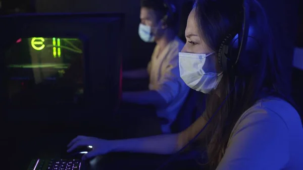 Vue latérale de la femme dans les masques de visage perd dans les jeux vidéo dans le club informatique moderne. — Photo