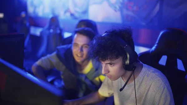 Молодой человек дает советы своему другу, пока он играет в видеоигры в современном киберспортивном клубе — стоковое фото