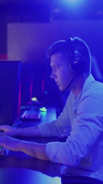 Siber spor müsabakası VERTICAL VIDEO 'da kulaklık takmış genç bir adamın video görüntüsü.