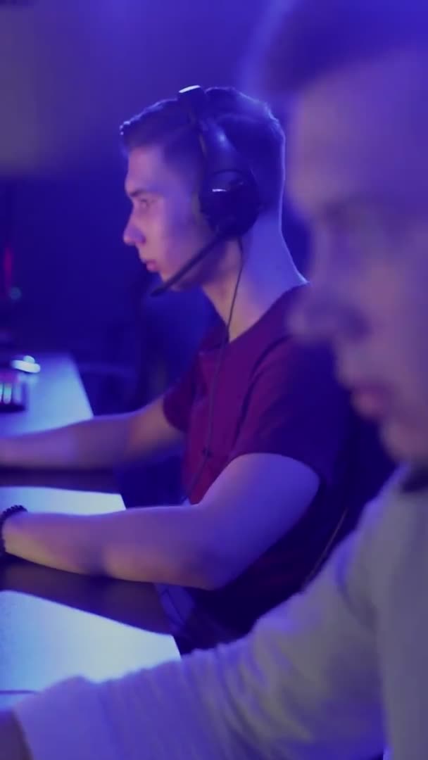 Dwóch młodych przyjaciół gra w grę online w klubie komputerowym. VIDEO WERTYCZNE — Wideo stockowe