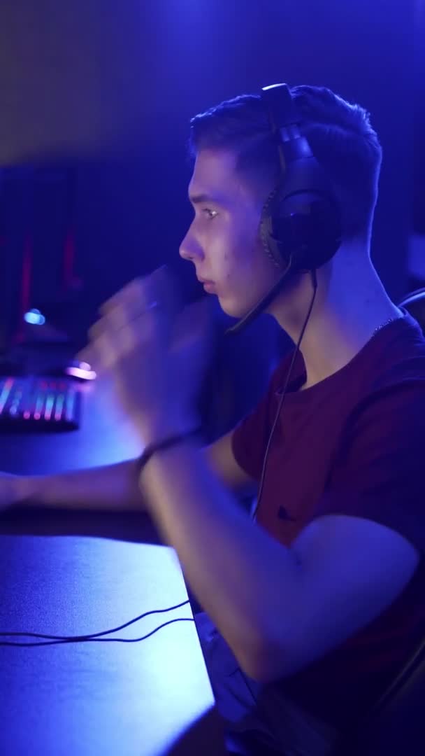 Des jeunes hommes en casque sont assis devant un ordinateur, jouent dans un club informatique. VIDEO VERTICALE — Video