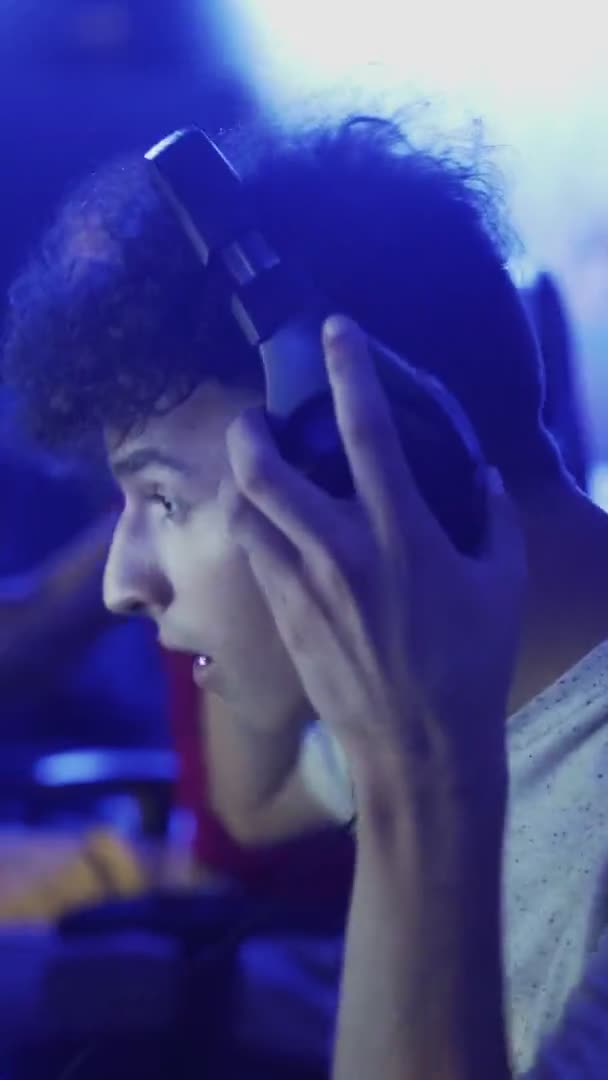 Joven lleva auriculares y se prepara para jugar en un videojuego VÍDEO VERTICAL — Vídeos de Stock
