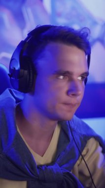 Konsantre genç adam monitörün önünde oturur ve VERTICAL VIDEO bilgisayar kulübünde bir video oyunu oynar.