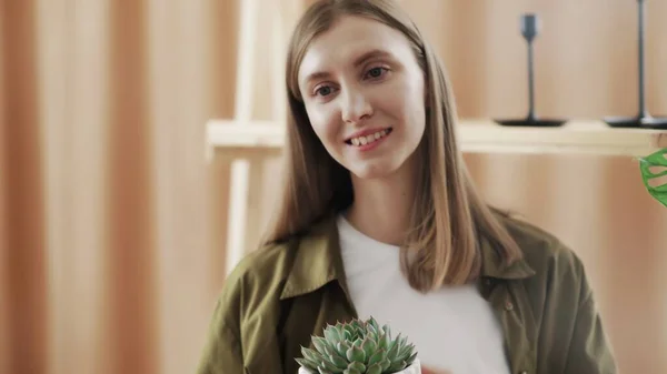 Young female gardener smiles and posing on camera with her cactus in hands. — Stock Photo, Image