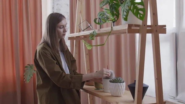 Young woman touches cares for plants. Attractive woman admiring her home plants in pots. — Stock Photo, Image