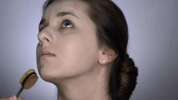 Processo de Maquiagem Profissional para mulher bonita e linda sentada no estúdio. Maquiagem Artista aplica corretor — Fotografia de Stock