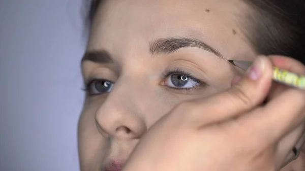 Processo de Maquiagem Profissional para mulher bonita e linda sentada no estúdio. Maquiagem Sobrancelhas de maquiagem de artista — Fotografia de Stock