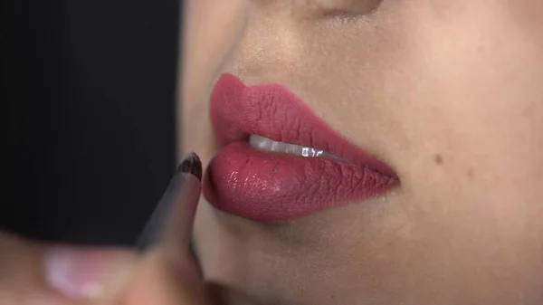 Macro tiro de maquiagem profissional para mulher bonita e linda sentada no estúdio. Maquiagem Artista aplica batom vermelho nos lábios — Fotografia de Stock