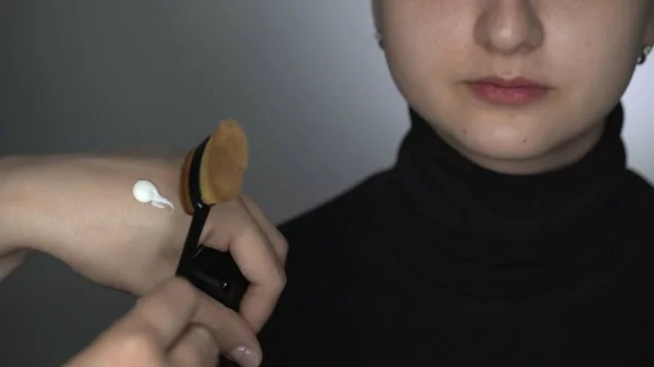 Zbliżenie make-up artysta robi profesjonalny makijaż dla młodej kobiety w studiu kosmetycznym. Make up Artist używa pędzla do nakładania makijażu, kremu lub podkładu. — Zdjęcie stockowe