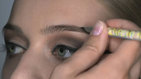 Makroaufnahme einer Visagistin, die junge Frauen im Schönheitsstudio professionell schminkt. Make-up Artist Make-up Augenbrauen — Stockfoto