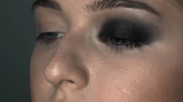 Macro de maquillaje artista haciendo maquillaje profesional para mujer joven en el estudio de belleza. Maquillaje Artista hace que el maquillaje ojos ahumados de un tono negro con cepillo especial de un hermoso modelo — Foto de Stock