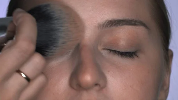 Makeup artist making professional make-up για νεαρή γυναίκα στο στούντιο ομορφιάς. Make up Καλλιτέχνης εφαρμόζει σκόνη με ένα μεγάλο πινέλο — Φωτογραφία Αρχείου