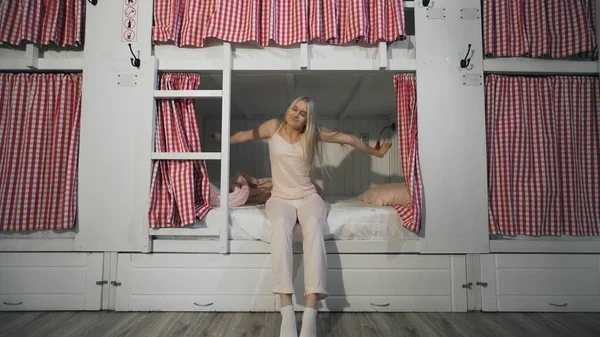 Young attractive woman stretches in bed in the hostel room — Stock Photo, Image