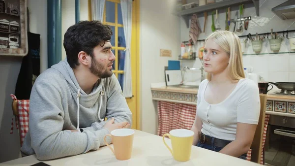 Young couple talking and drinking tea together on a kitchen — Stock Photo, Image