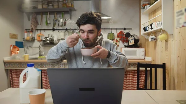 Business man working laptop computer and eats Corn Flakes Cereal at home kitchen. Stock Image