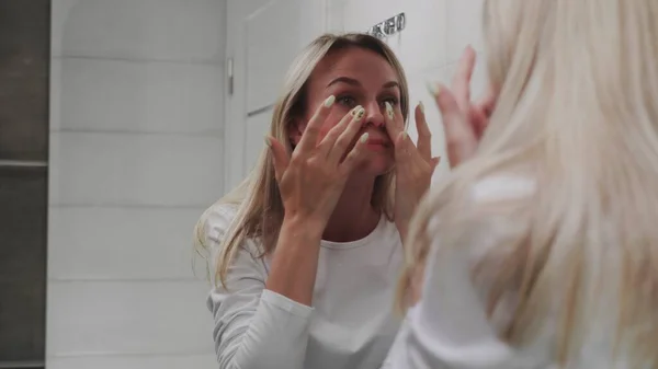 Beautiful Woman looking at the mirror and touching her face — Stock Photo, Image