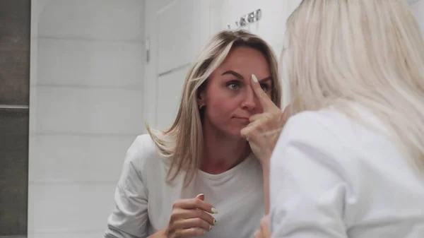 Hermosa mujer mirando al espejo y tocándose la cara — Foto de Stock