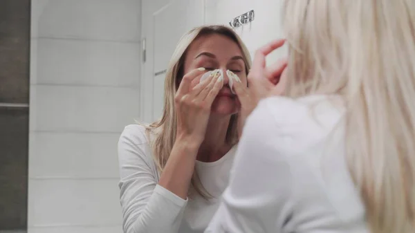 Losyon süren ve aynaya bakan kadın doğal güzelliğin ve sağlığın tadını çıkarıyor.