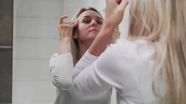 Femme appliquant la lotion et regardant dans le miroir profiter de la beauté naturelle et saine — Photo