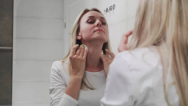 Mujer aplicación de loción y mirando en el espejo disfrutar de la belleza natural y saludable — Foto de Stock