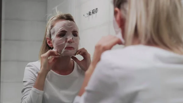 거울을 보면서 얼굴에 마스크를 쓴 여자 — 스톡 사진